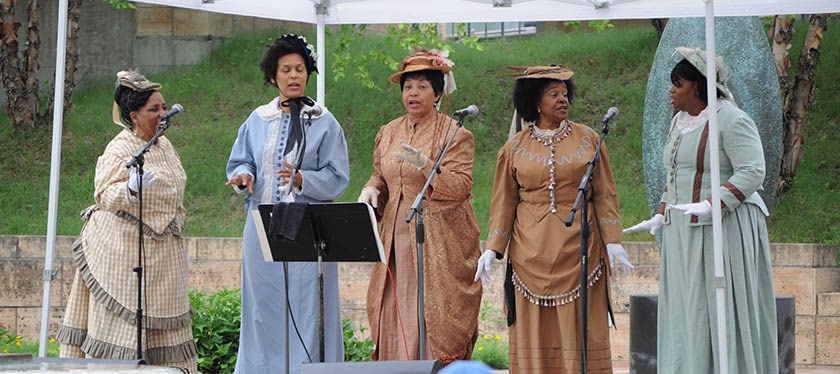Five women in historical dress presenting a musical program