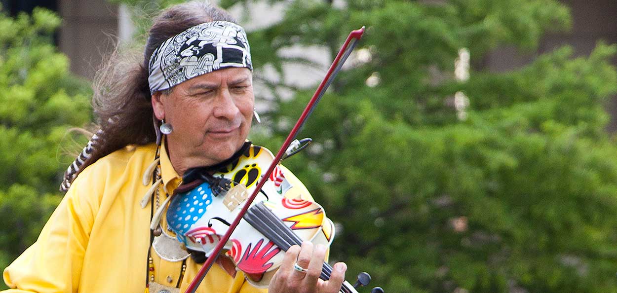 Native man playing brightly painted violin